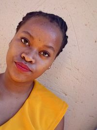 Close-up portrait of a smiling young woman against wall