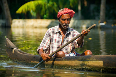 Portrait of man holding boat in lake