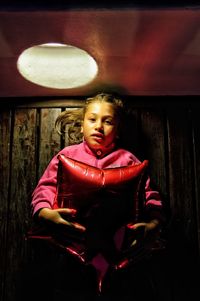 Close-up of cute girl standing against illuminated wall