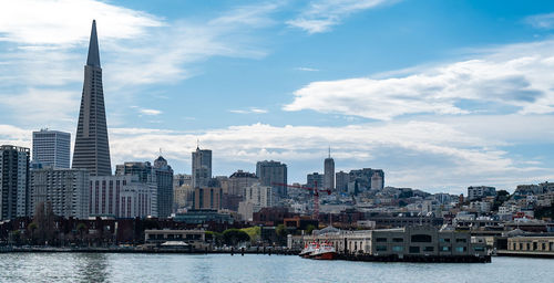 View of buildings at waterfront against cloudy sky
