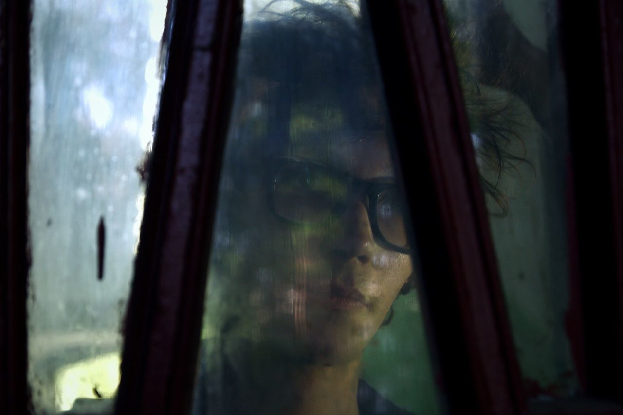 CLOSE-UP OF REFLECTION OF MAN IN GLASS WINDOW