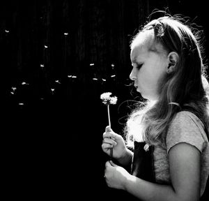 Portrait of young woman looking away against black background