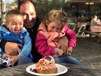 Happy father with son and daughter sitting at table