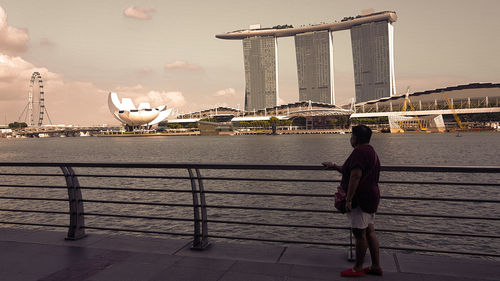 Rear view of man on bridge over river in city