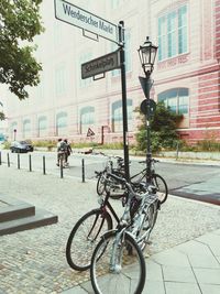 Bicycles parked by sign post on sidewalk