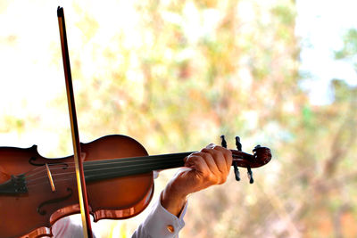 Cropped hand of man playing violin outdoors