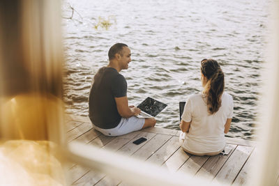 Couple talking while working at patio seen through window