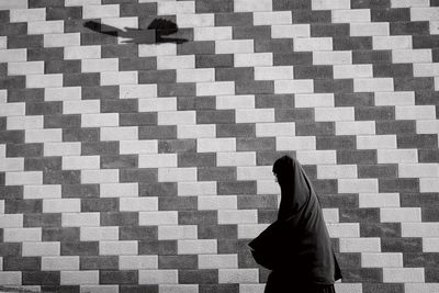 Rear view of woman standing against brick wall