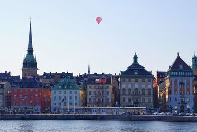 Residential buildings by river against clear sky