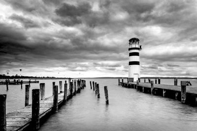 Pier on sea against cloudy sky