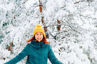 Portrait of young woman standing on snow covered field