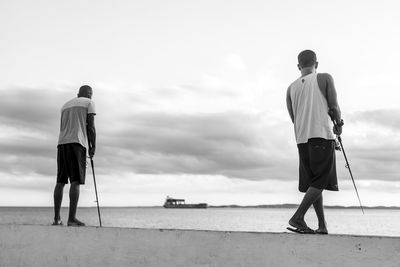 Rear view of men walking on beach