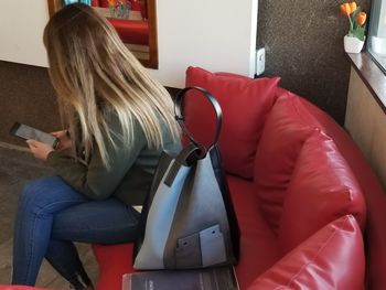 Woman using mobile phone while sitting on sofa at home