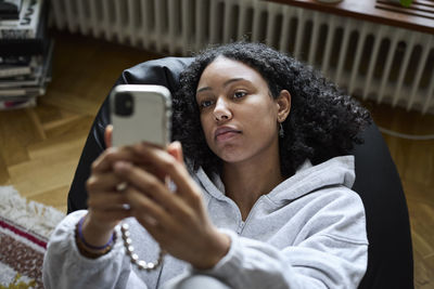 Young woman lying on bean bag and taking selfie