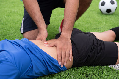 Midsection of man massaging friend back on soccer field