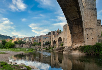 Arch bridge over river against sky