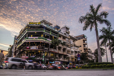 Cars on road by building in city against sky