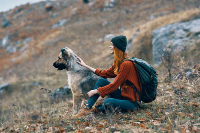 Side view of dog sitting on landscape