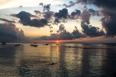 Scenic view of sea against cloudy sky at sunset