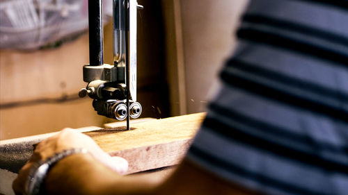 Midsection of man working with wood on machine