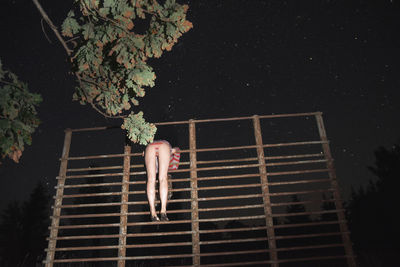 Low angle view of woman standing on built structure at night