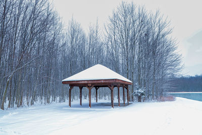 Gazebo on snow covered field against clear sky