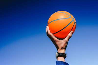 Man playing with ball against clear blue sky