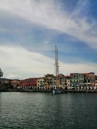 Sea by buildings against sky in city