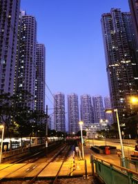 Illuminated cityscape against clear blue sky at night