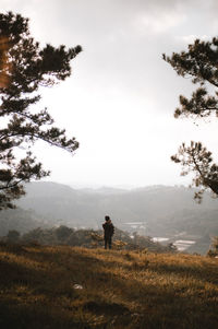 Rear view of man standing on mountain against sky