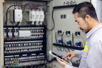 Close up hand of engineer or electrician man working check the electrical system with tablet