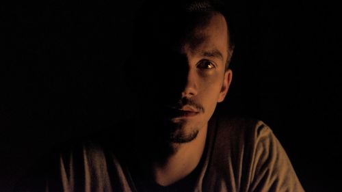 Close-up portrait of young man against black background