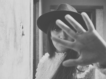 Portrait of young woman wearing hat hiding face with hands