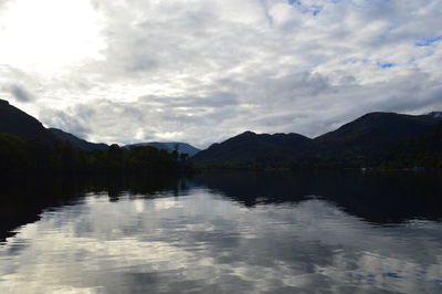 Scenic view of lake and mountains against cloudy sky