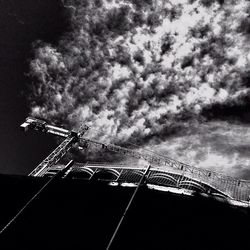 Low angle view of crane against cloudy sky