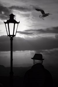 Rear view of silhouette man standing against sky during sunset