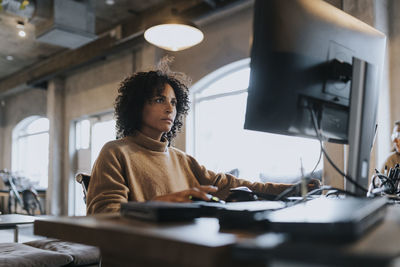 Dedicated female hacker working on computer at desk in startup company