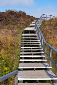 Staircase leading towards bridge against sky