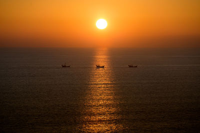 Aerial view of boats on sea against orange sky during sunset