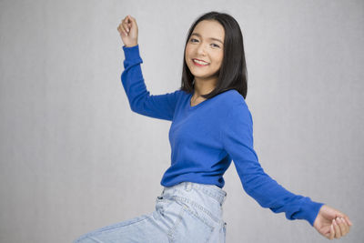 Portrait of a smiling young woman standing against wall