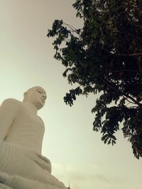 Low angle view of statue against trees against sky