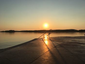 Silhouette person on lake against sky during sunset