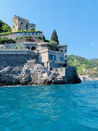 Buildings at waterfront against blue sky