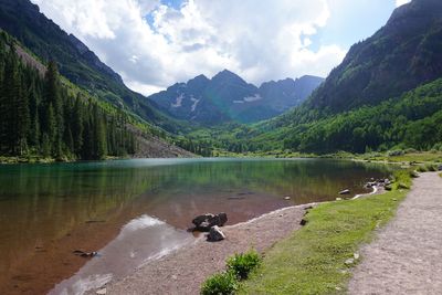 Scenic view of lake surrounded by mountains against cloud - sky