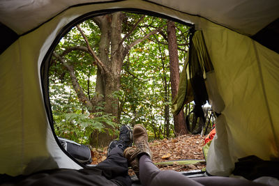 Low section of friends relaxing in tent at forest