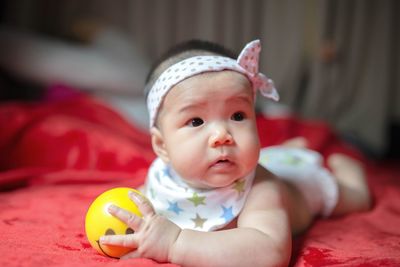 Portrait of cute baby girl lying on bed