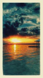 Scenic view of sea against cloudy sky during sunset