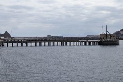 Pier on river against cloudy sky