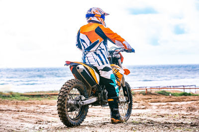 Horse riding motorcycle on beach against sky