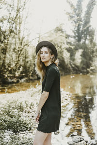 Side view of smiling young woman standing against trees